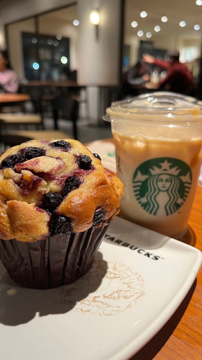Muffin de arándanos junto a un café frío para llevar